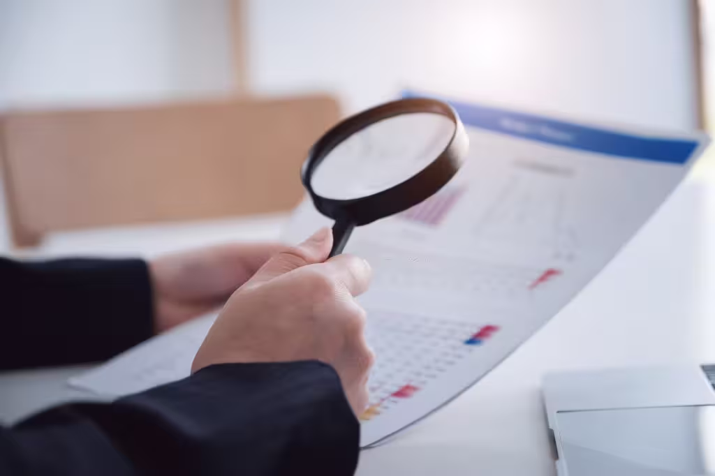 Person examining report with magnifying glass